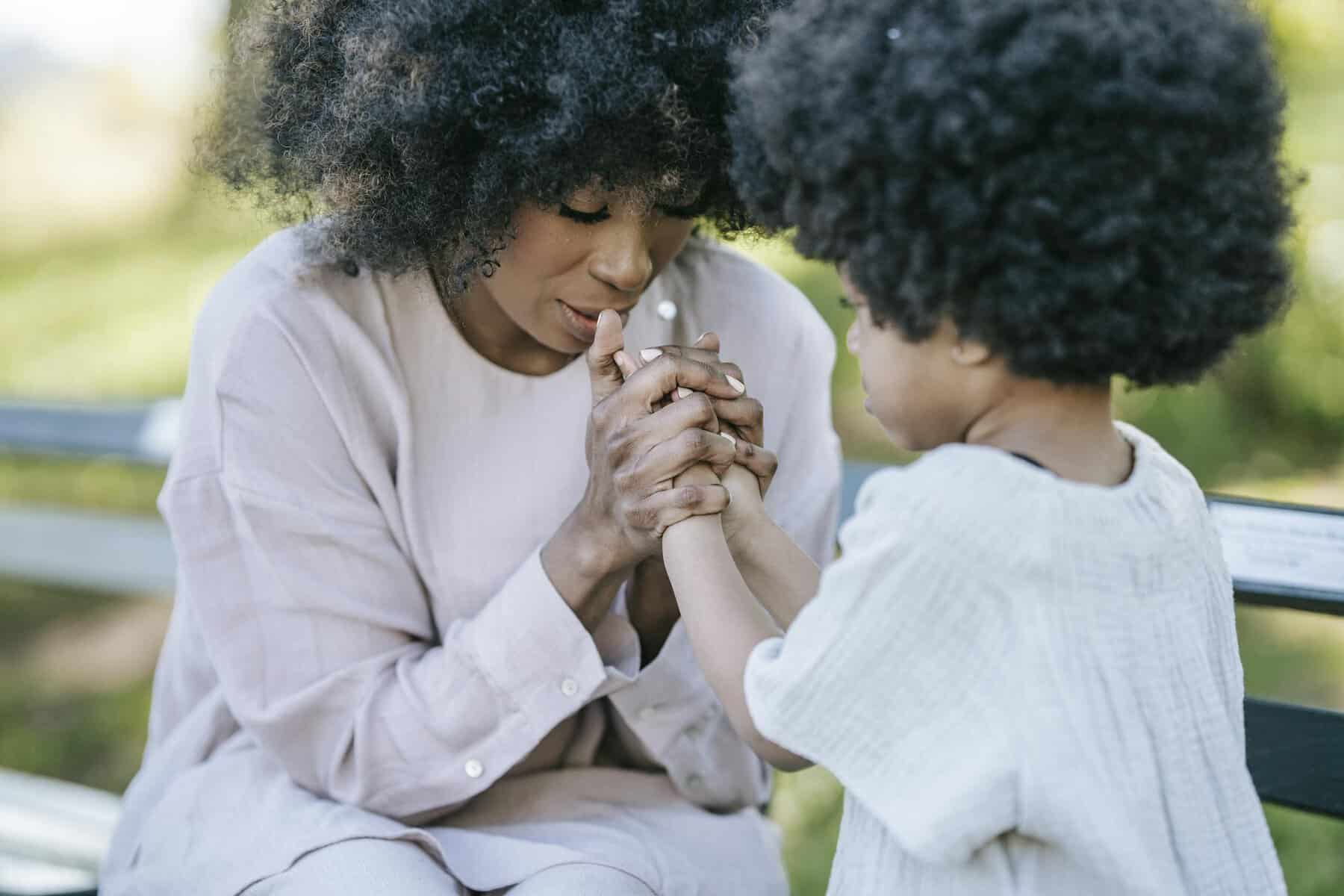 A heartwarming moment between a mother and daughter holding hands outdoors.